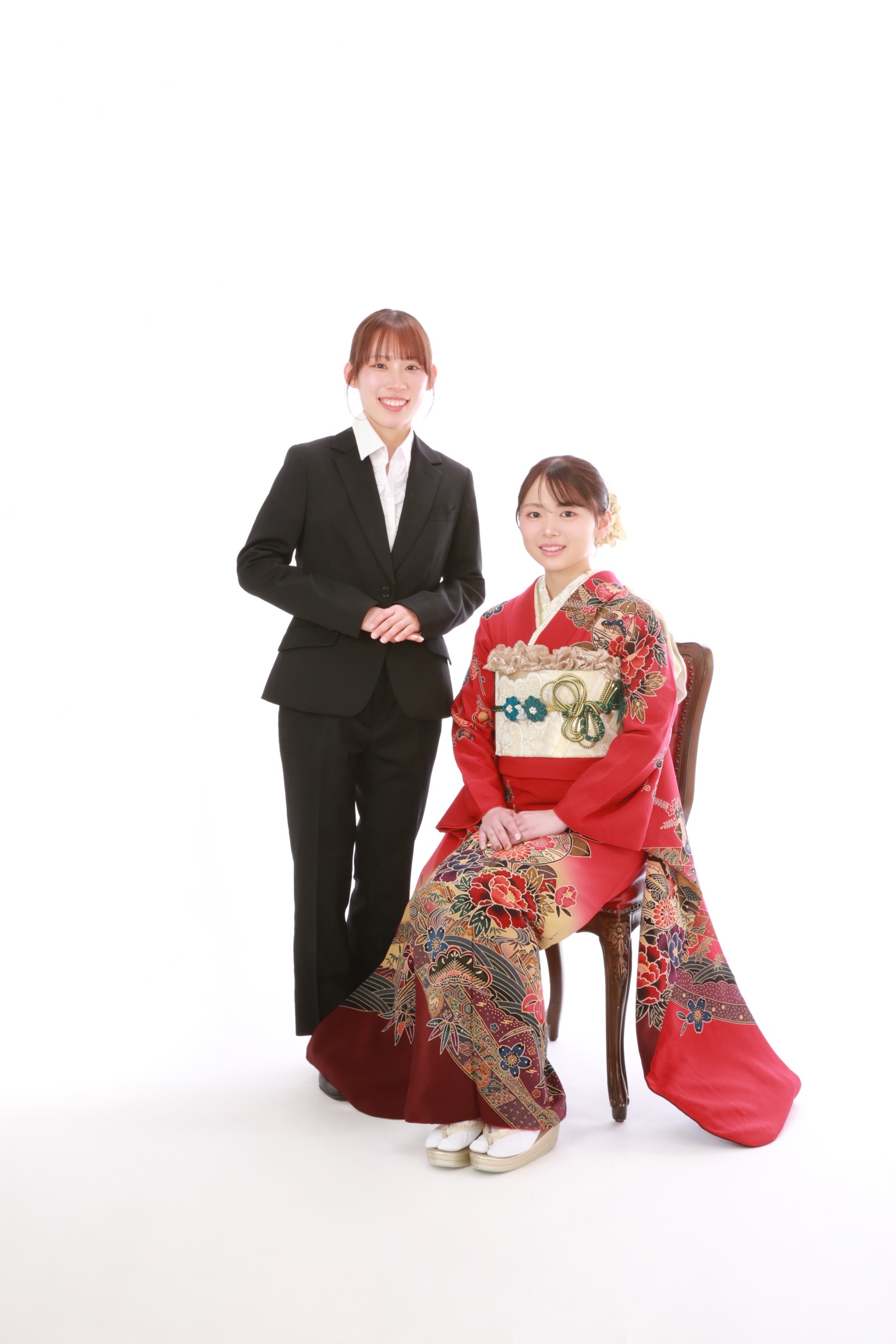 赤い振袖姿のお嬢様と姉妹の記念写真