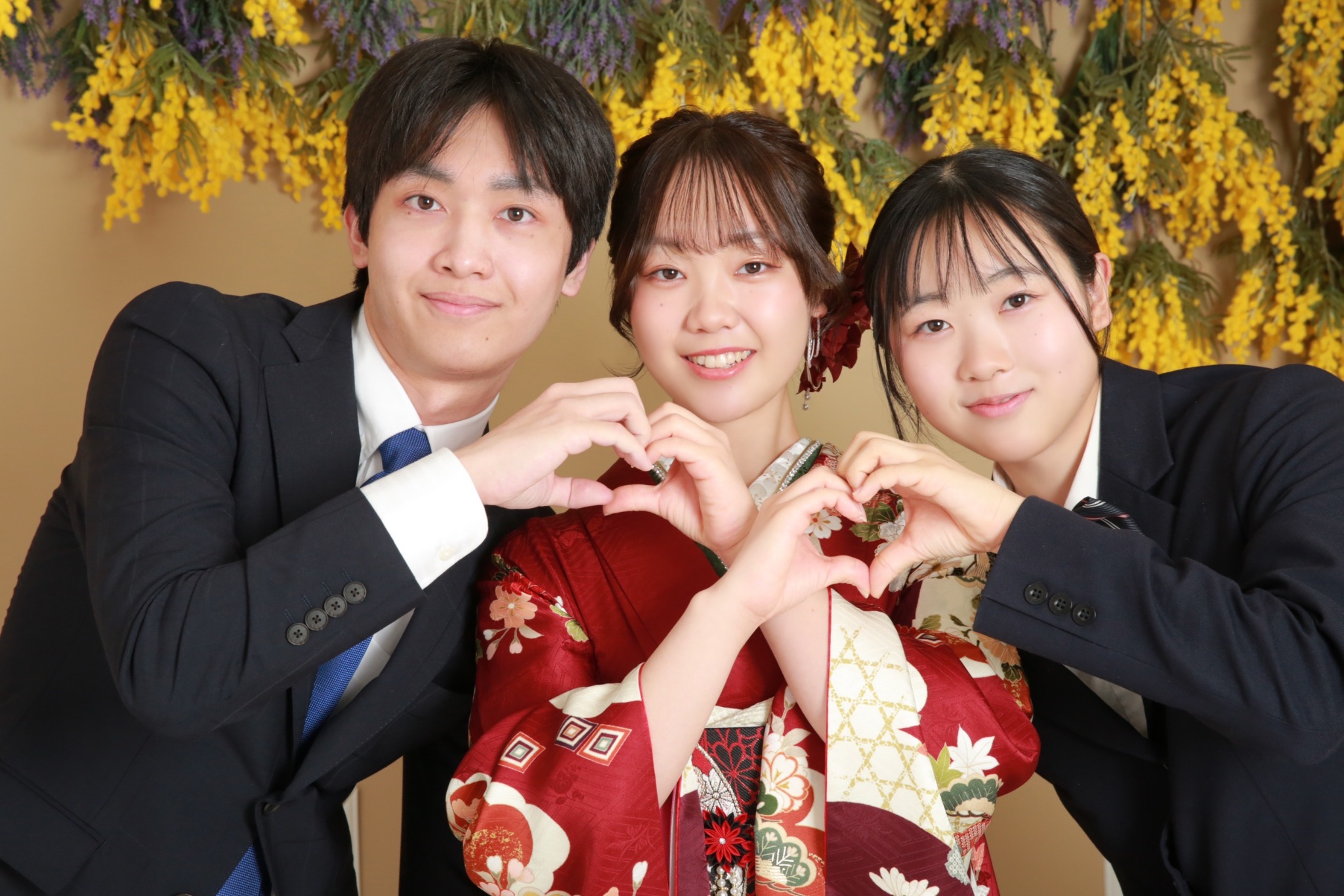 振袖姿のお嬢様と兄弟姉妹がハートを作る記念写真
